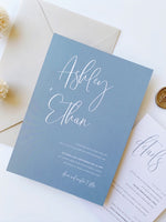 Ashleigh's Calligraphy Wedding Invitation in dusty blue, printed on 250gsm pearlescent card stock.